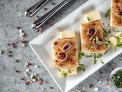 Fette di focaccia con filetti di acciughe marinate in casa con aglio,olio e prezzemolo, sul lettino di burro image